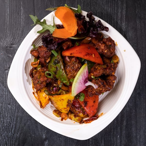 Everest Cuisine's chili chicken, a vibrant Indian dish with bell peppers, onions, and radish.
