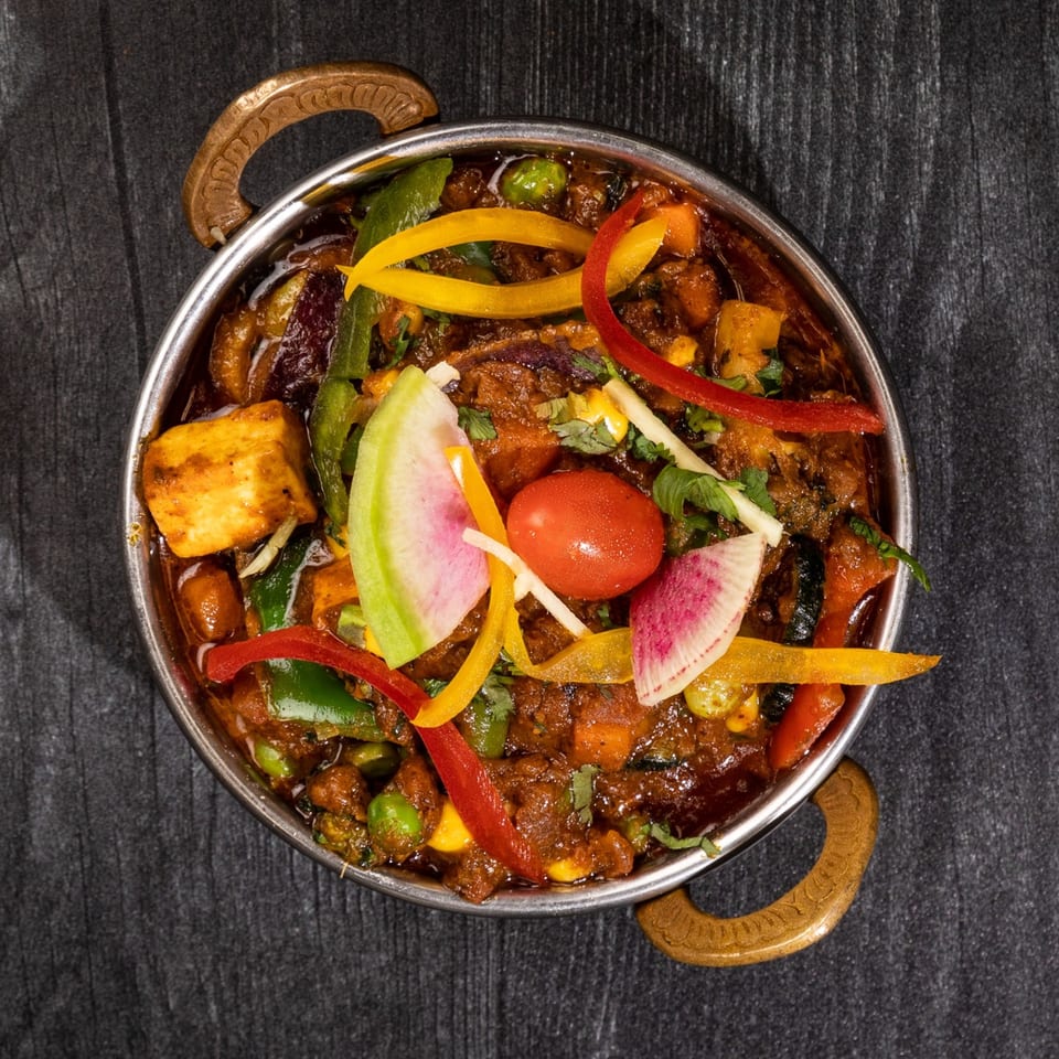 Everest Cuisine's Indian curry with paneer, vegetables, and spices in a metal serving bowl.