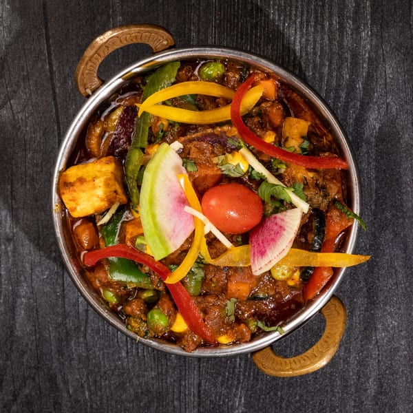 Everest Cuisine's Indian curry with paneer, vegetables, and spices in a metal bowl.