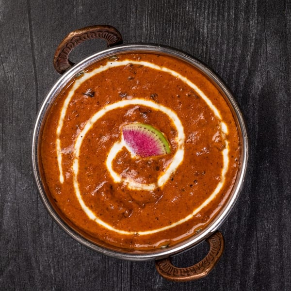 Everest Cuisine's Dal Makhani, a rich Indian lentil dish, garnished with cream and a watermelon radish slice.