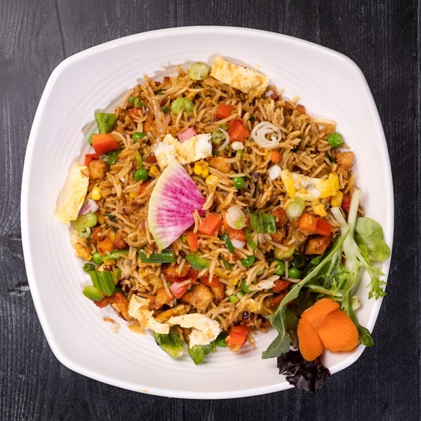 Everest Cuisine's vegetable fried rice with egg, peas, carrots, and a radish slice.