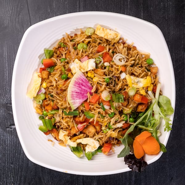 Everest Cuisine's fried rice with vegetables, egg, and a slice of watermelon radish on a white plate.
