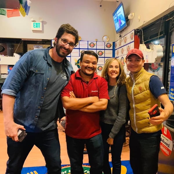 Four smiling people, two men and two women, posing together inside Everest Cuisine restaurant.