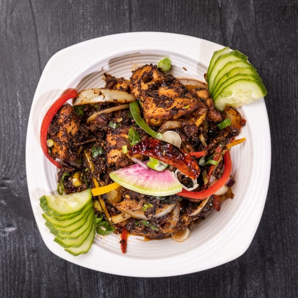 Everest Cuisine's Indian dish with dark-spiced chicken, onions, peppers, and cucumber slices.