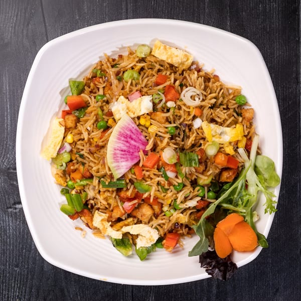 Everest Cuisine's vegetable fried rice with egg, peas, carrots, and a radish slice.