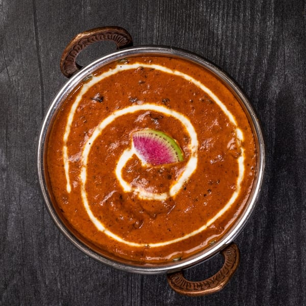 Everest Cuisine's Indian curry, garnished with cream swirls and a slice of watermelon radish.