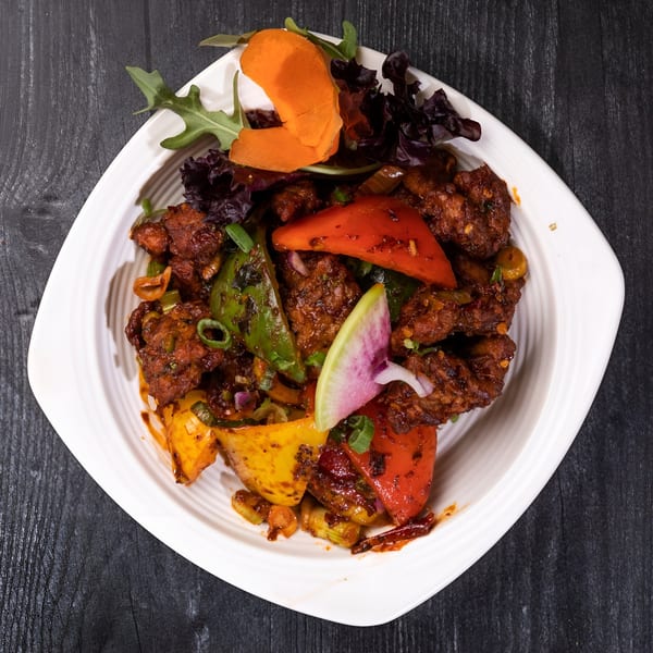 Everest Cuisine's chili chicken, a spicy Indian dish with bell peppers and garnish.