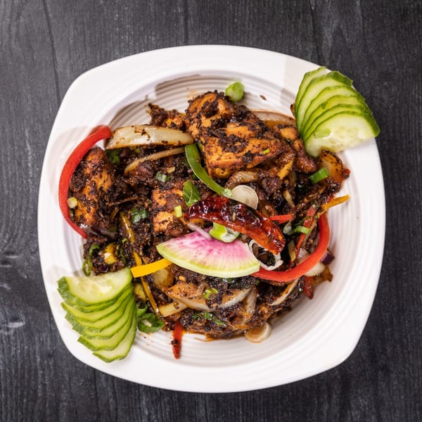 Everest Cuisine's Indian dish with dark-spiced chicken, bell peppers, onions, and cucumber slices.