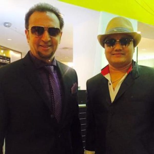 Two men in suits and sunglasses, one wearing a fedora, stand smiling at Everest Cuisine.