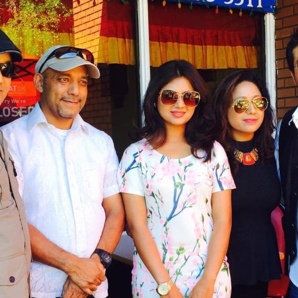 Three people, two women and one man, stand smiling in front of Everest Cuisine.